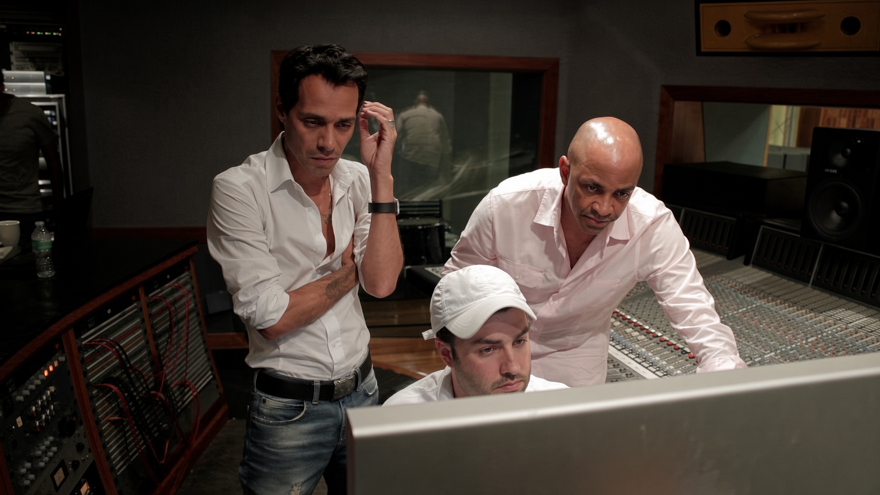 Three collaborators working together at a recording studio console