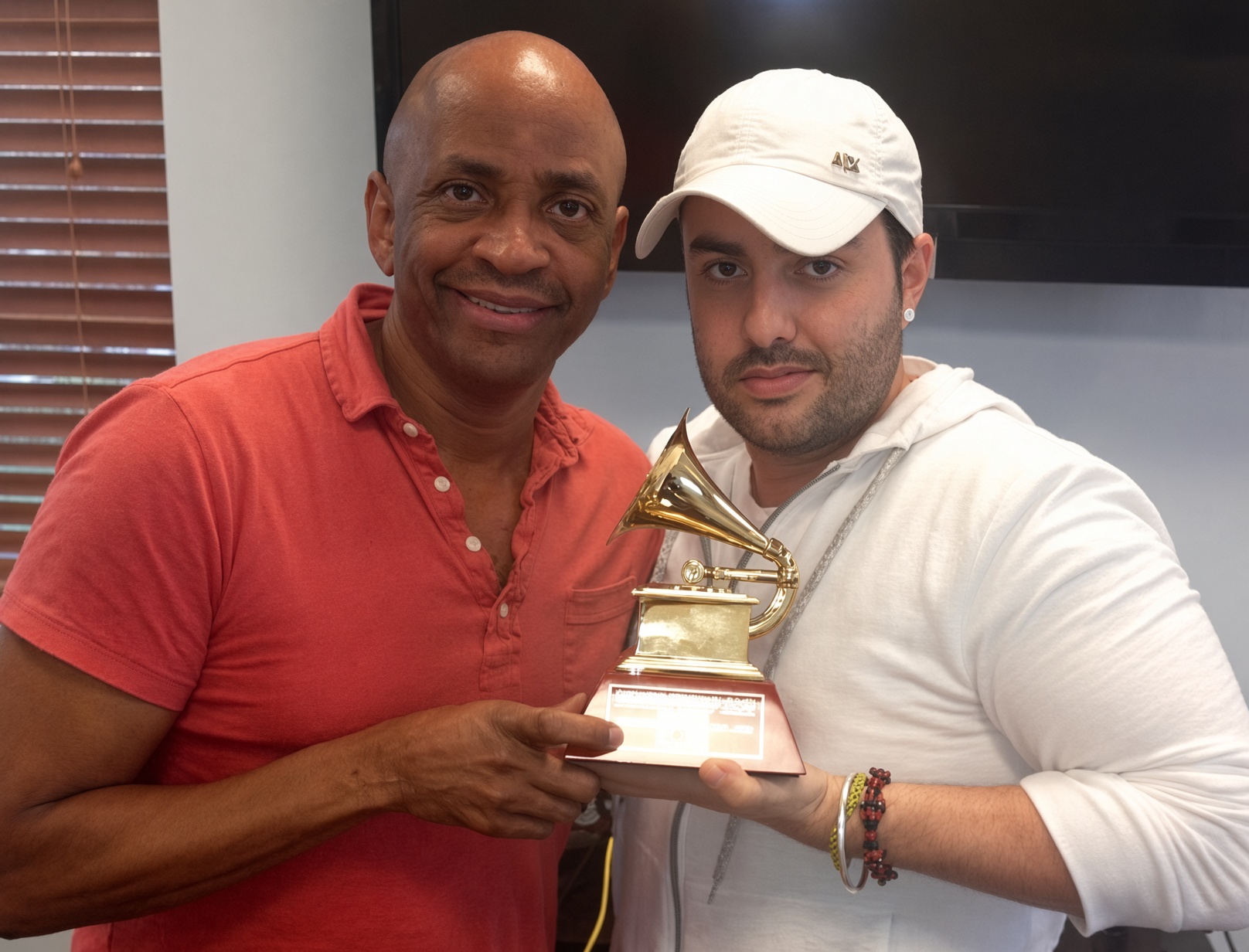 Two collaborators holding a gold gramophone award together